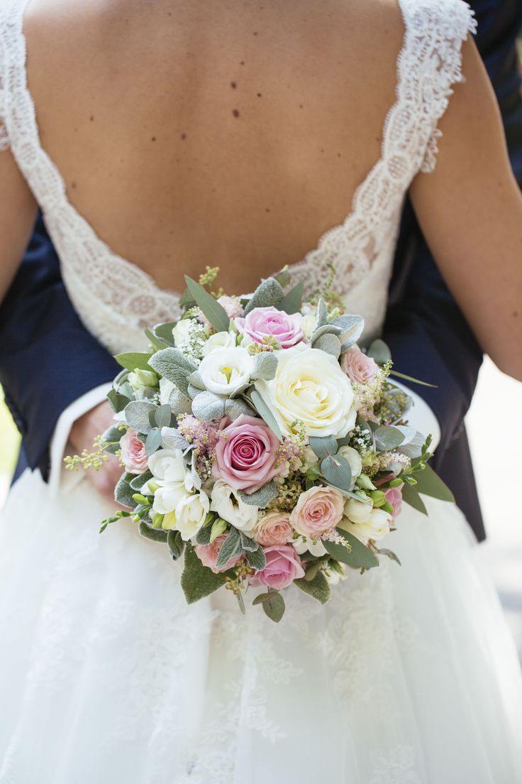 a close up of a bride holding a bouquet of flowers in front of her back