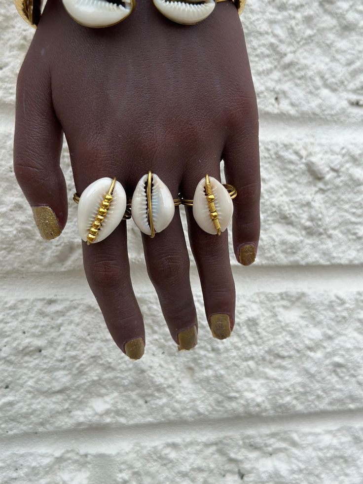 This artisanal Cowry shell and Brass adjustable Ring adds a touch of bohemian charm to any outfit. Handmade with precision and attention to detail, each ring offers a unique and stylish look. A perfect addition to your jewelry collection. sold as 1 per price Bohemian Adjustable Hand Wrapped Rings, Bohemian Midi Rings For Jewelry Making, Unique Gold Jewelry For Vacation, Hand Wrapped Shell Jewelry, Handmade Adjustable Shell Jewelry, Handmade Open Ring Jewelry For Beach, Unique Handmade Adjustable Midi Rings, Handmade Adjustable Unique Midi Rings, Handmade Rings For Beach