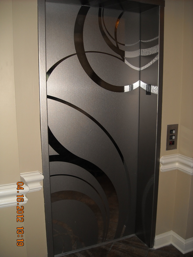 a glass door with an artistic design on the front and side panels, in a hallway