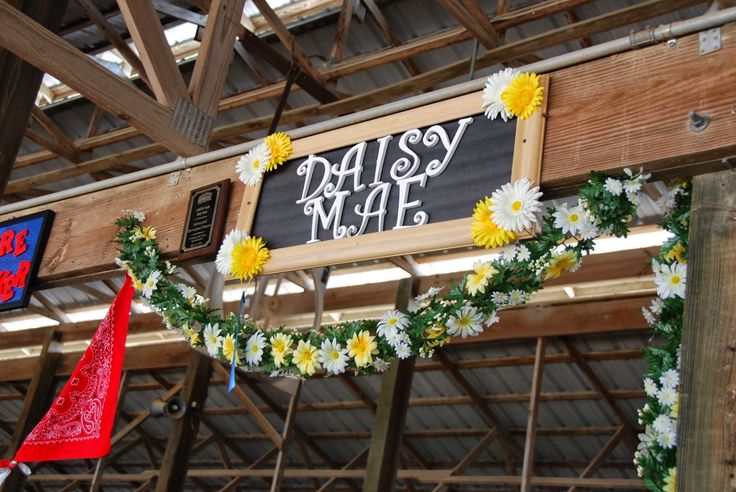 daisy garlands are hanging from the ceiling in front of a sign