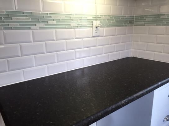 a black counter top in a kitchen with white cabinets