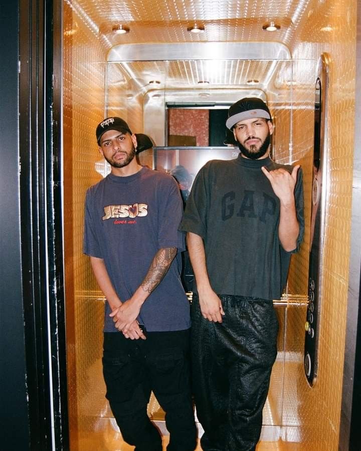 two men standing in an elevator with one pointing at the camera