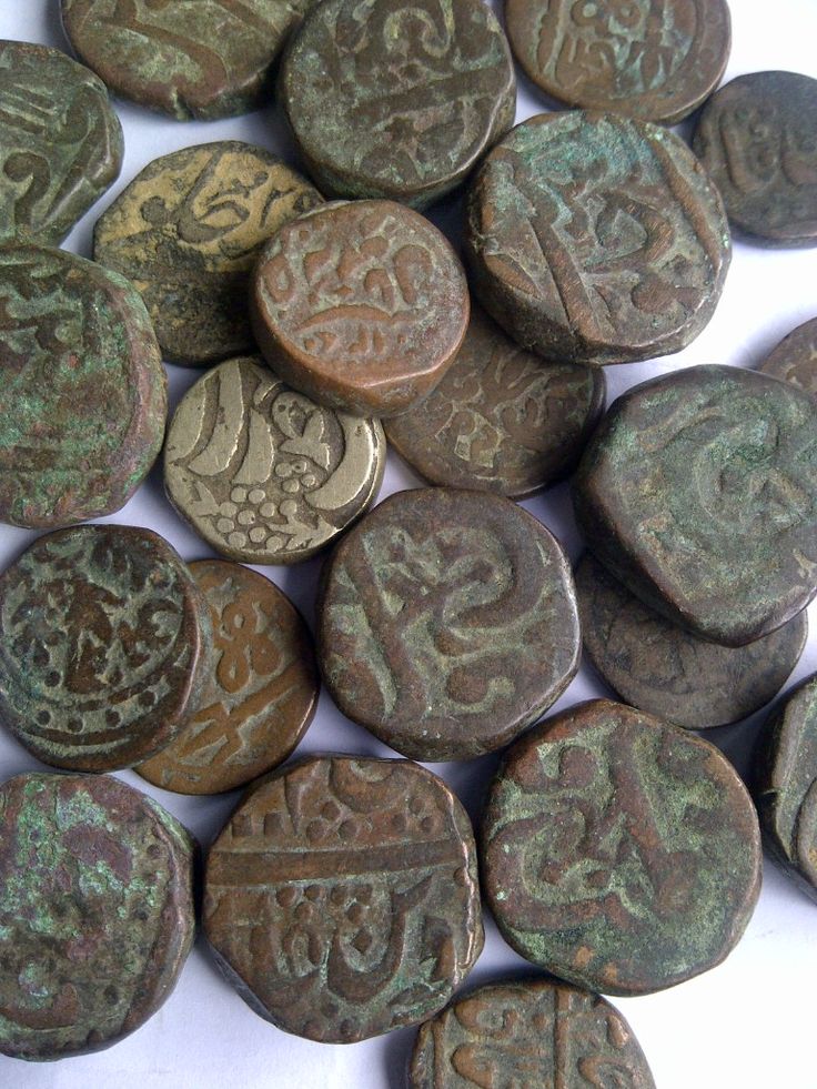 some very pretty old metal buttons on a white surface with letters and numbers painted on them