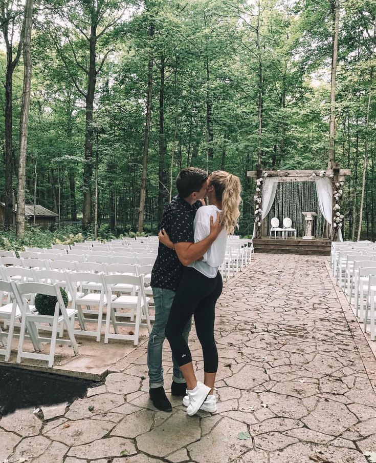 a man and woman standing next to each other in front of an outdoor ceremony area