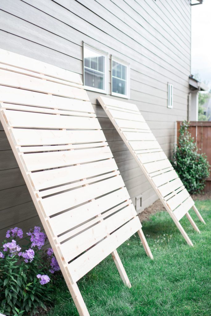 three wooden slats sitting in the grass next to a house with purple flowers growing out of them