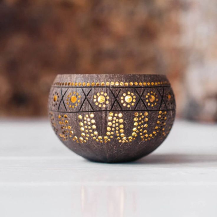 a decorative wooden bowl with gold dots on the inside is sitting on a white surface