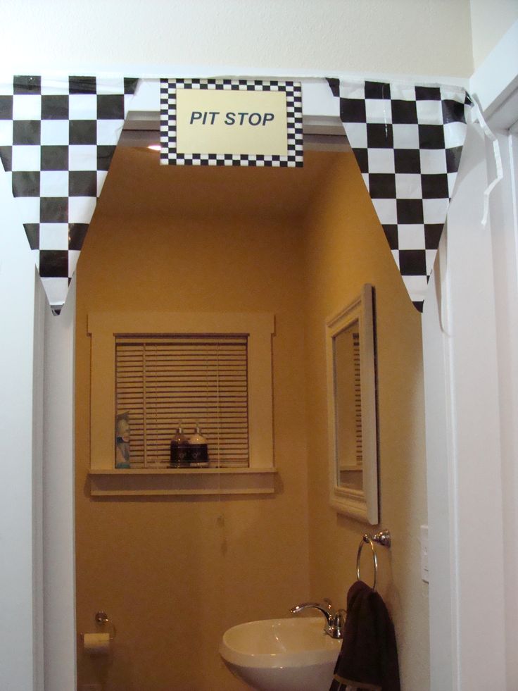 a bathroom with a checkered wall and window above the sink that says pitt stop