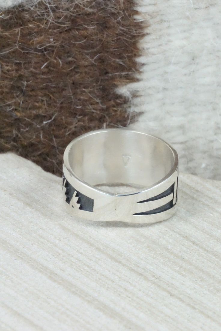 This sterling silver ring was made by Hopi silversmith Timothy Mowa. The inside is stamped sterling.Size: 12Length: 1"Free shipping on all orders! We ship with USPS and always include tracking. All orders ship within a day of payment.Returns are accepted up to 30 days after you receive your order. Just send us a message. Our shop offers cash back or store credit. The item must be returned in new condition. Artisan Sterling Silver Wide Band Ring, Artisan Engraved Sterling Silver Ring 925, Artisan Sterling Silver Engraved Hallmarked Ring, Symbolic Sterling Silver Stamped Rings, Symbolic Stamped Sterling Silver Rings, Stamped Sterling Silver Wide Band Jewelry, Sterling Silver Ring With Thick Band Stamped 925, Sterling Silver Rings With Stamped 925 And Thick Band, Sterling Silver Rings With Thick Band, Stamped 925