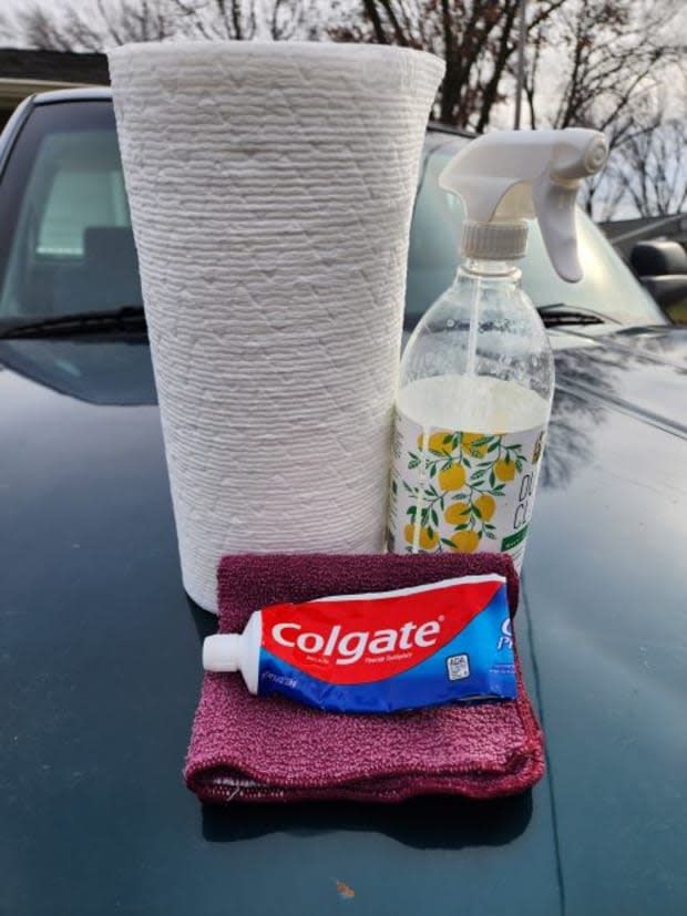 a close up of a car's hood with a bottle of cleaner and toilet paper on it