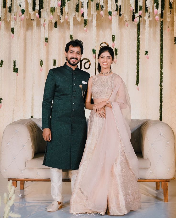 a man and woman standing next to each other in front of a floral decorated stage