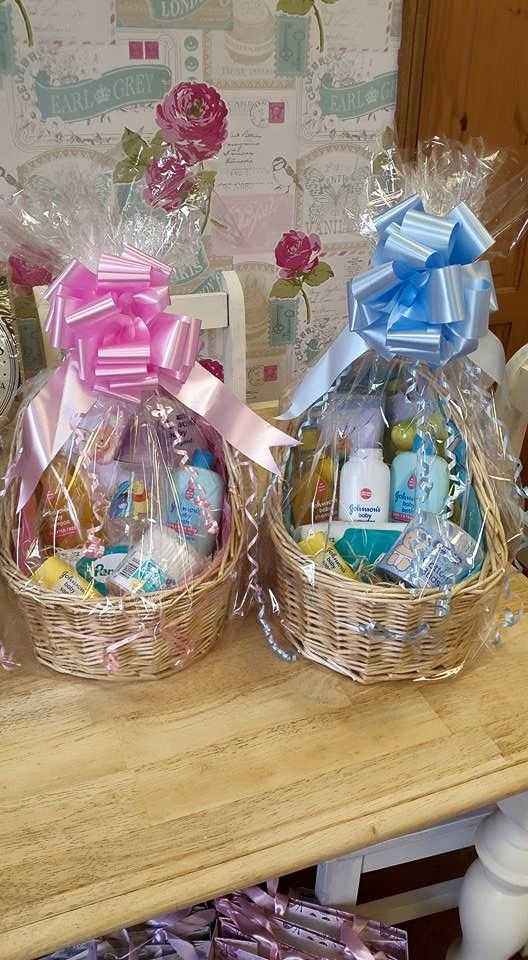 two baskets filled with baby items sitting on top of a wooden table next to each other