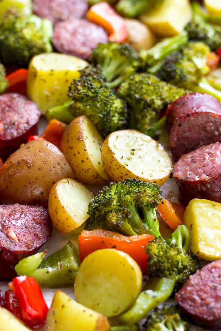 a plate full of sausage, potatoes and broccoli with seasonings on it