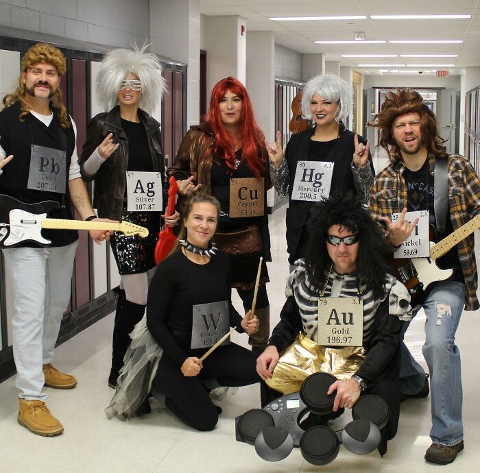 a group of people dressed in costumes posing for a photo with guitars and wigs