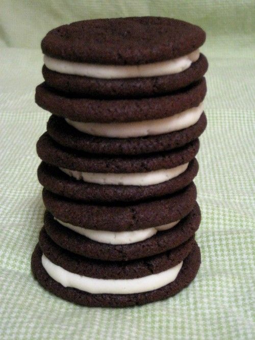 a stack of cookies with white frosting and chocolate chips on top, sitting on a green tablecloth