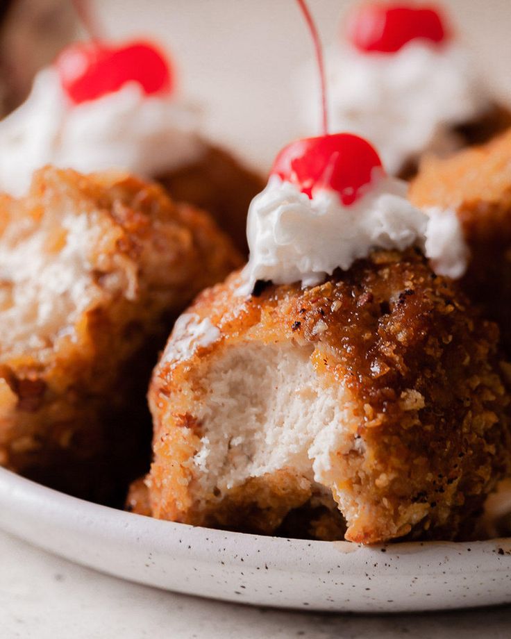 a white plate topped with pastries covered in whipped cream and cherries on top