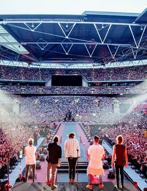 three men standing at the end of a stage in front of a large group of people