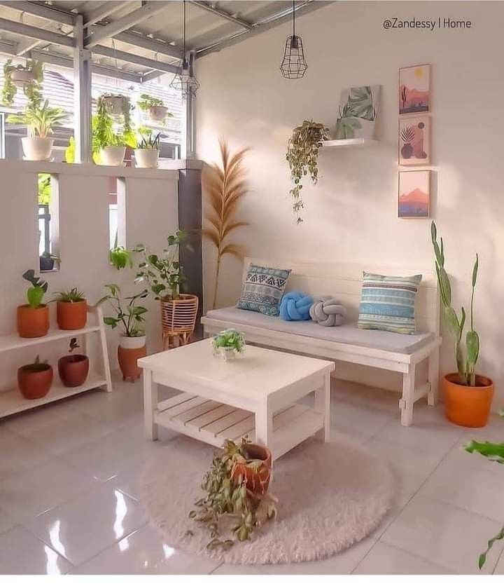 a living room filled with lots of potted plants next to a white couch and coffee table