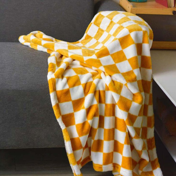 an orange and white checkered blanket sitting on top of a couch