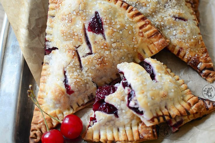 three cherry hand pies sitting on top of a table next to some cherries