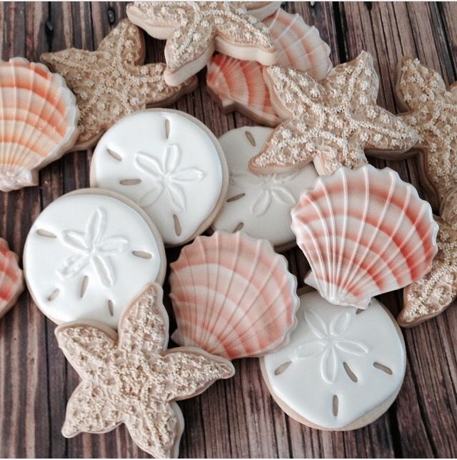 seashells and starfish decorated cookies on a wooden table