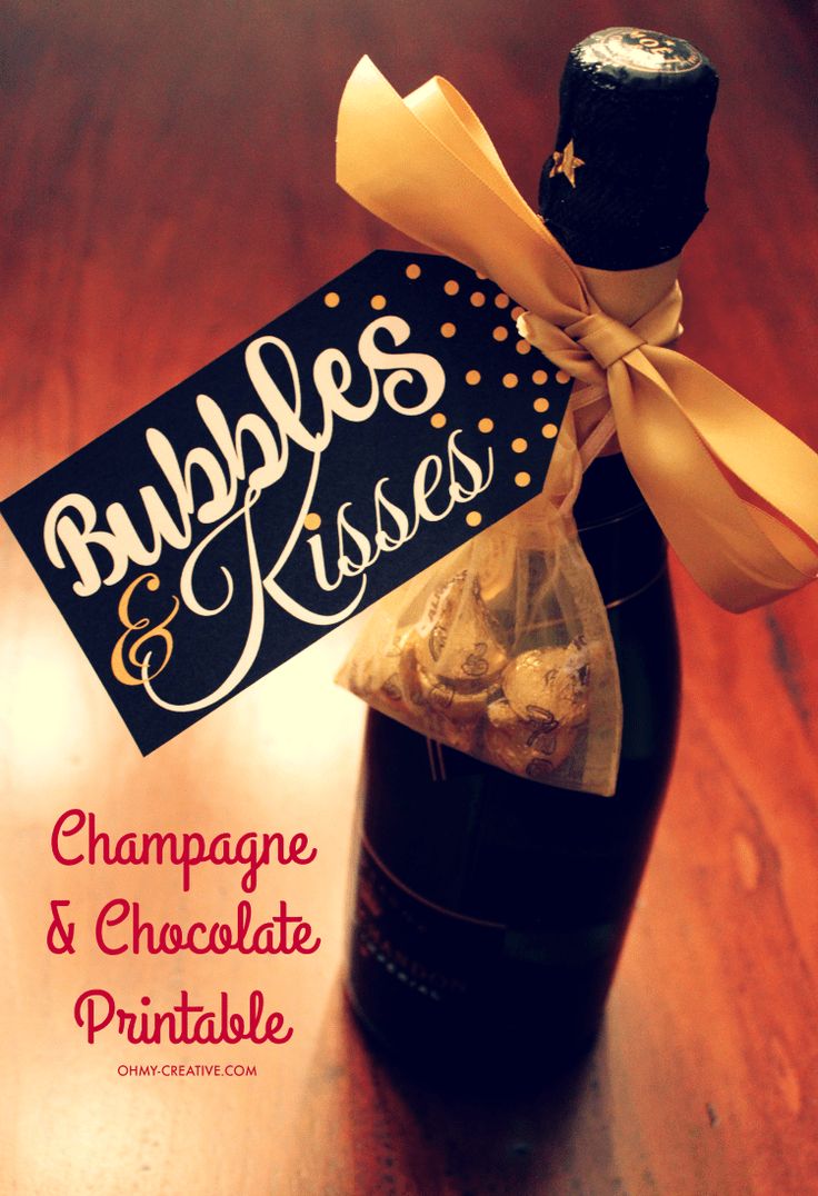 a bottle filled with champagne and chocolate covered pretzels on top of a wooden table