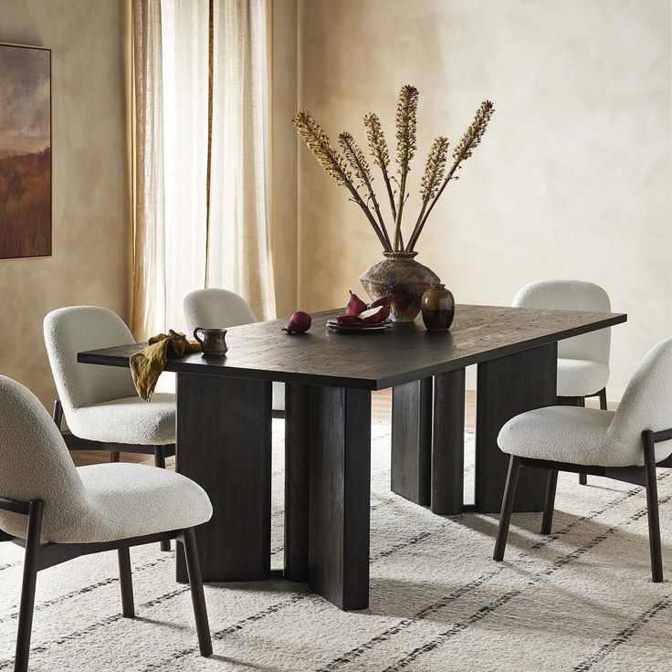 a dining room table with chairs and a vase filled with flowers on top of it