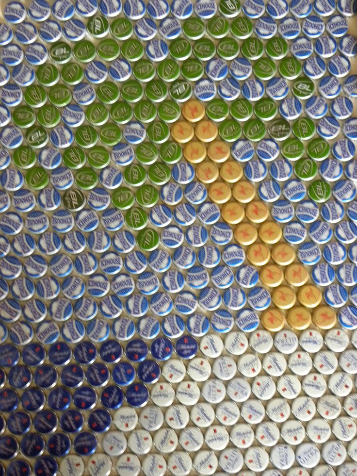 the bottle cap art is made to look like a tree and has green leaves on it