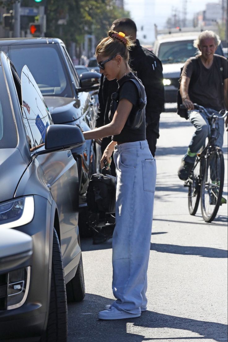 a woman standing next to a car on a street