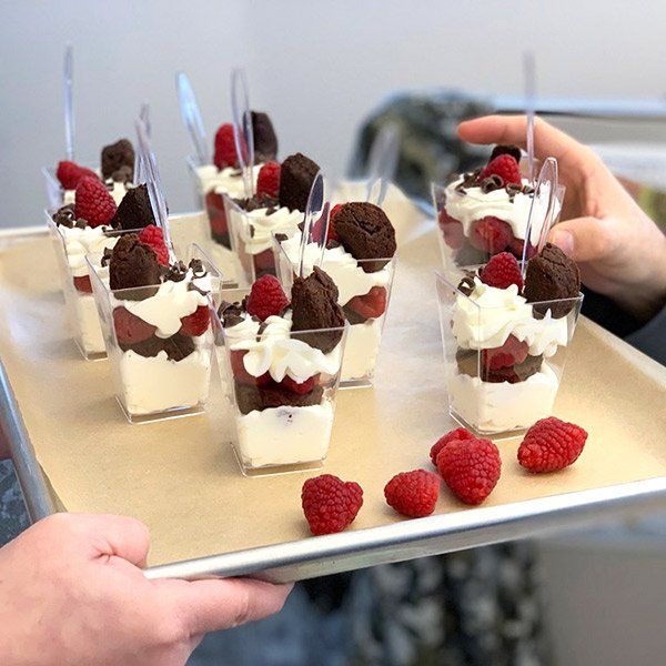 a tray with desserts on it being held by two hands