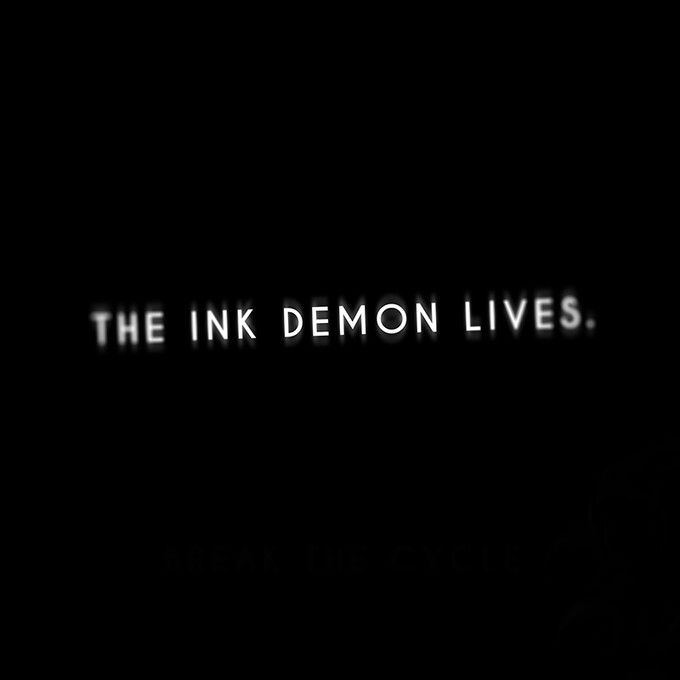 the ink demon lives logo in black and white on a dark background with text that reads,