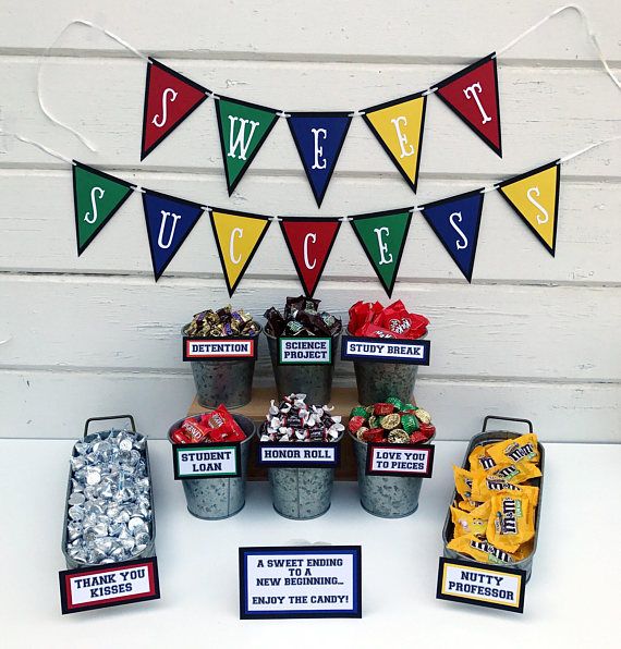 a table topped with buckets filled with candy next to bunting flags and cupcakes