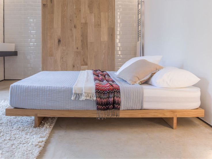 a bed sitting in the middle of a bedroom next to a wall mounted sink and mirror