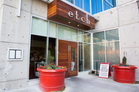 two large red planters are in front of the entrance to an office building with glass windows