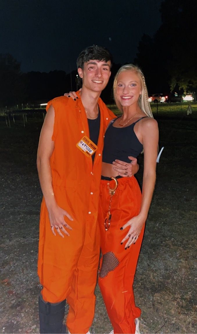 a man and woman in orange jumpsuits posing for the camera at an outdoor event