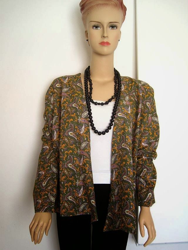 a mannequin wearing a necklace and jacket with beads on it's neck