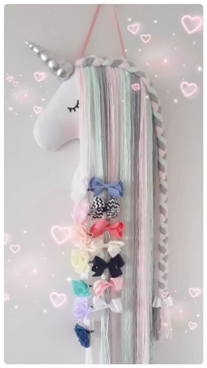 a unicorn head hanging from the side of a wall with hair clips attached to it