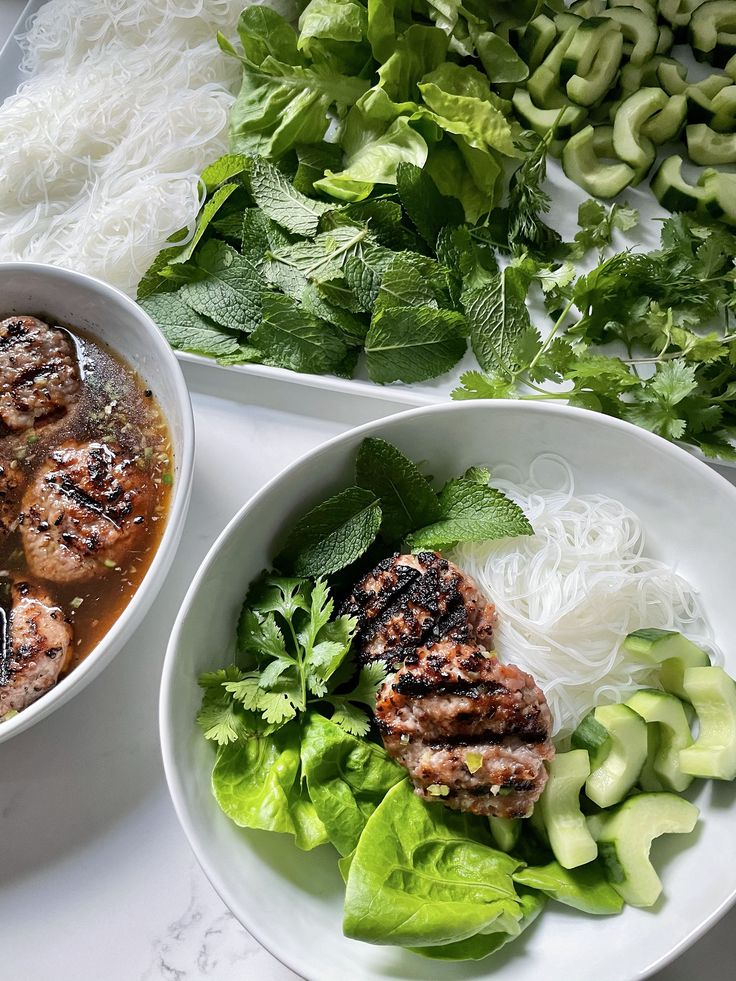 two bowls filled with meat and veggies on top of a white tablecloth