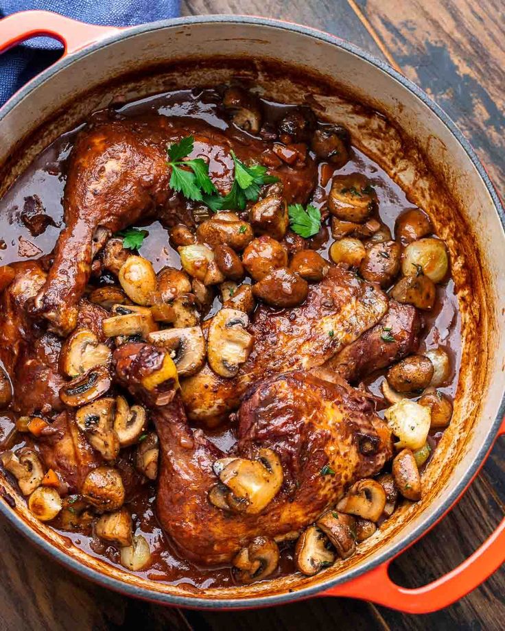 a pot filled with meat and mushrooms on top of a wooden table