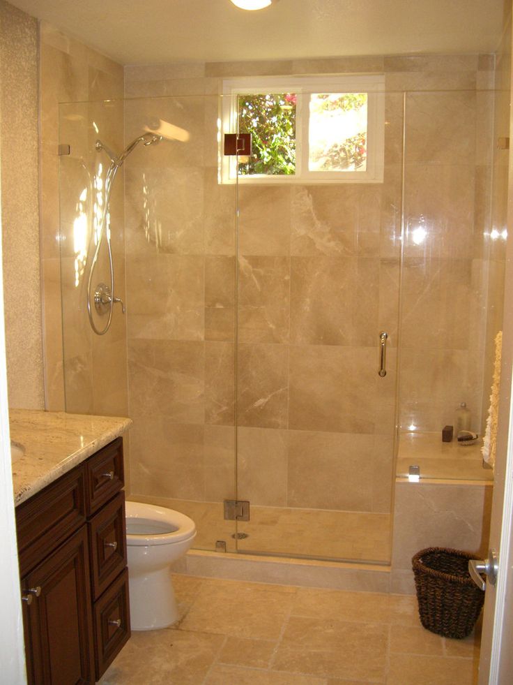 a bathroom with a walk in shower next to a white toilet and brown cabinetry