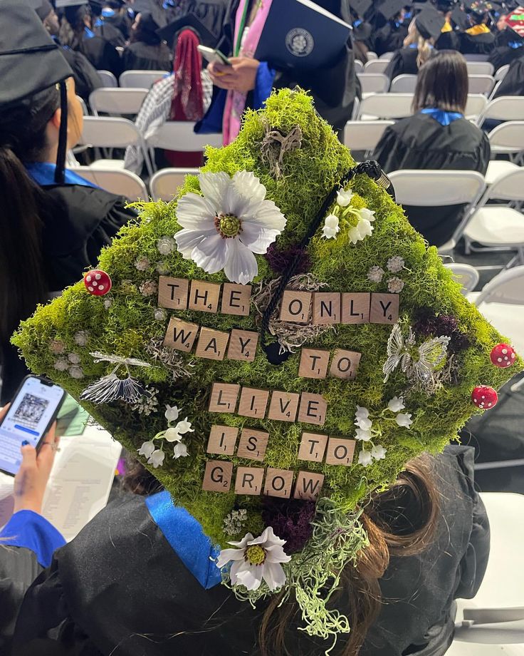 a woman wearing a graduation cap with words written on it and flowers in the shape of a heart