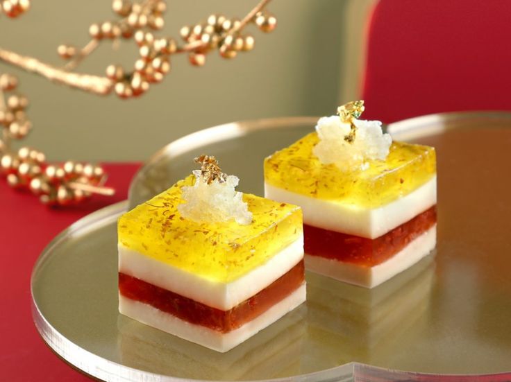 two desserts sitting on top of a silver plate next to a red tablecloth