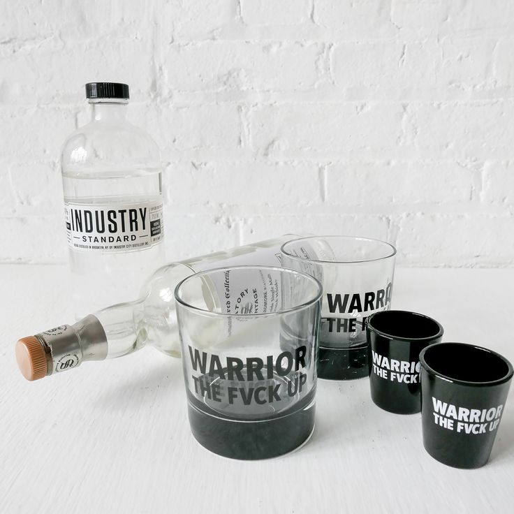 three shot glasses and a bottle sitting on a table