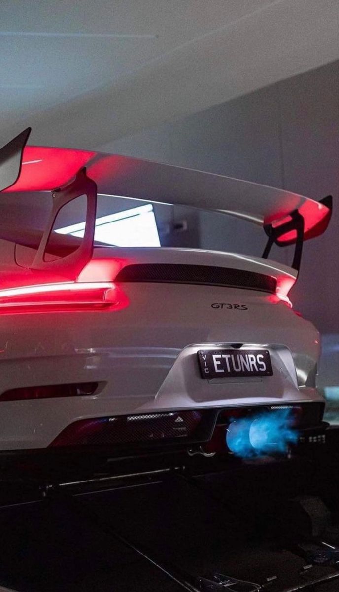 the rear end of a white sports car in a showroom with its lights on