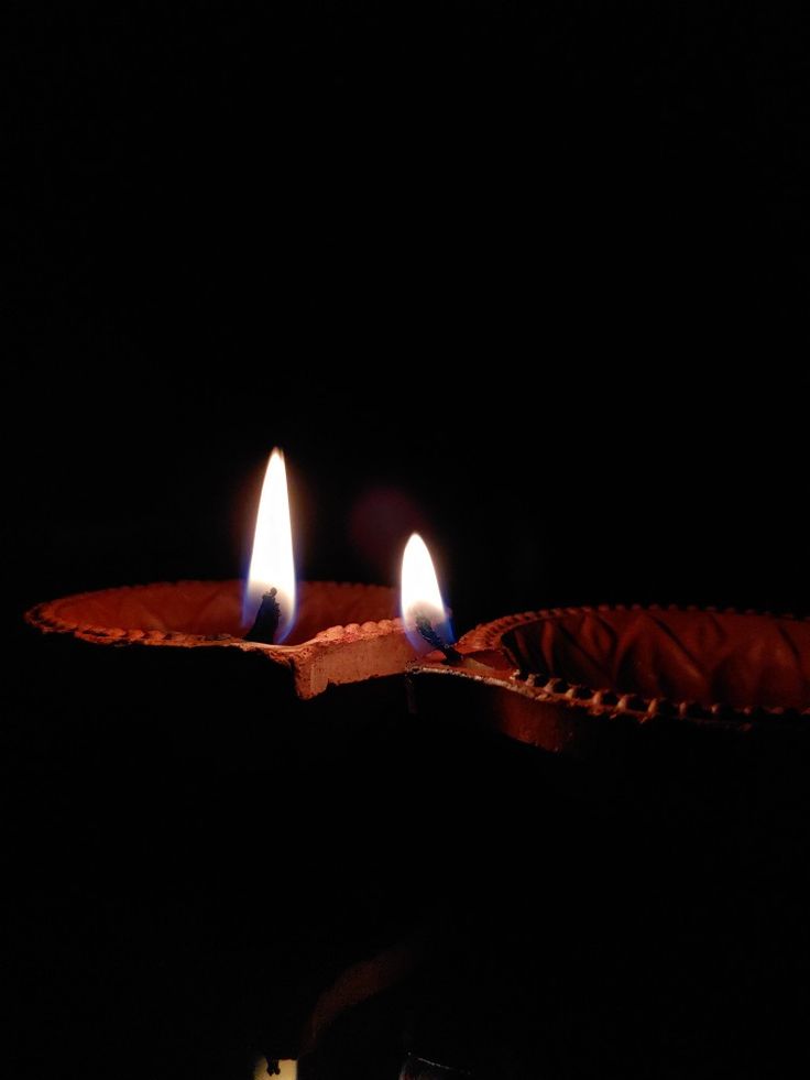 three lit candles sitting on top of a paper plate in the dark, with only one burning