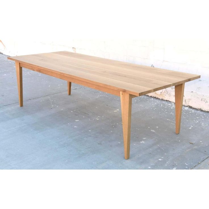 a wooden table sitting on top of a cement floor next to a white brick wall