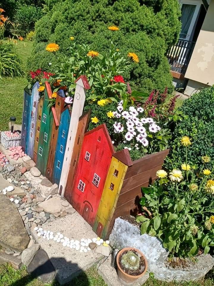 a garden filled with lots of colorful flowers and wooden houses on top of it's sides