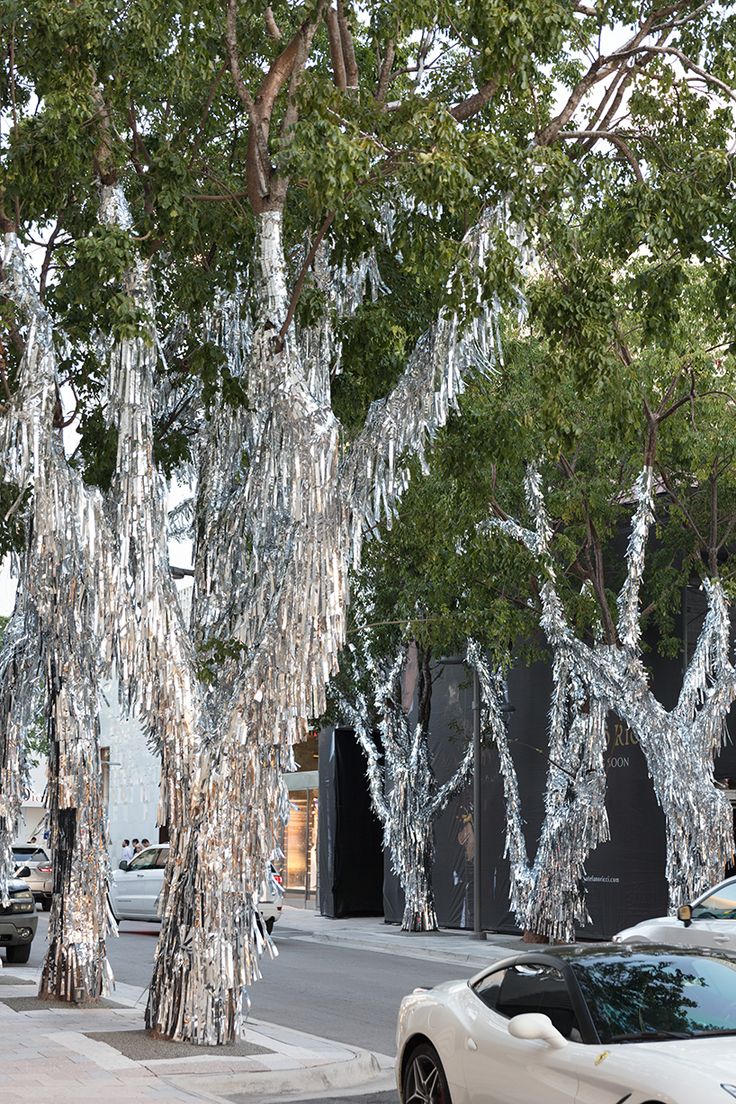 a white car parked on the side of a road next to trees covered in ice