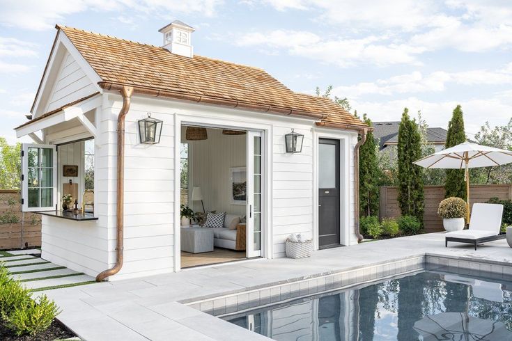 a small pool house with an outdoor living area next to it and a swimming pool