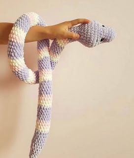 a person holding a knitted snake in their hand