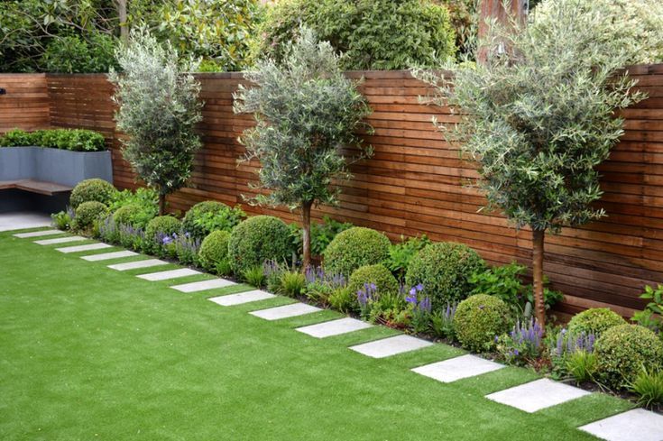 an image of a garden with grass and trees in the back yard, surrounded by wooden fence